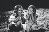 Zwei Mädchen halten Hand vor den Mund