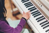 Kind mit einer Hand auf der Klaviertastatur