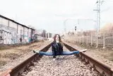 Frau mach Spagat auf Bahngleis